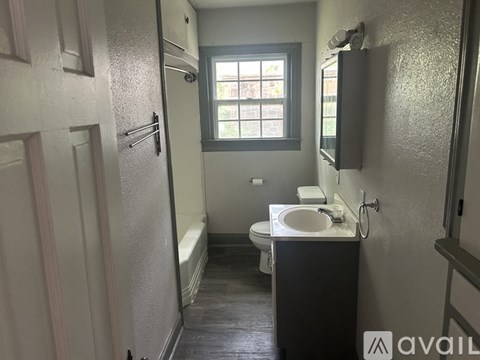 A bathroom with a toilet, sink, and window.