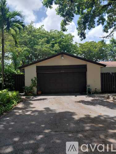 A two-car garage is situated in front of a house with a driveway and trees.