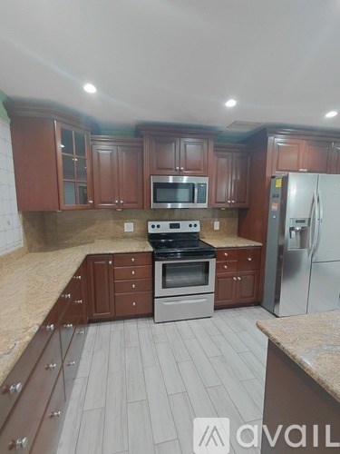 A kitchen with brown cabinets and a stainless steel refrigerator.