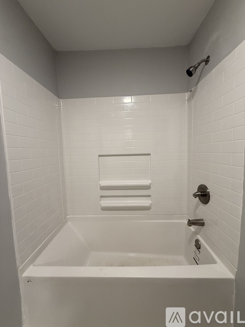 A white bathroom with a white tub and white tiles.