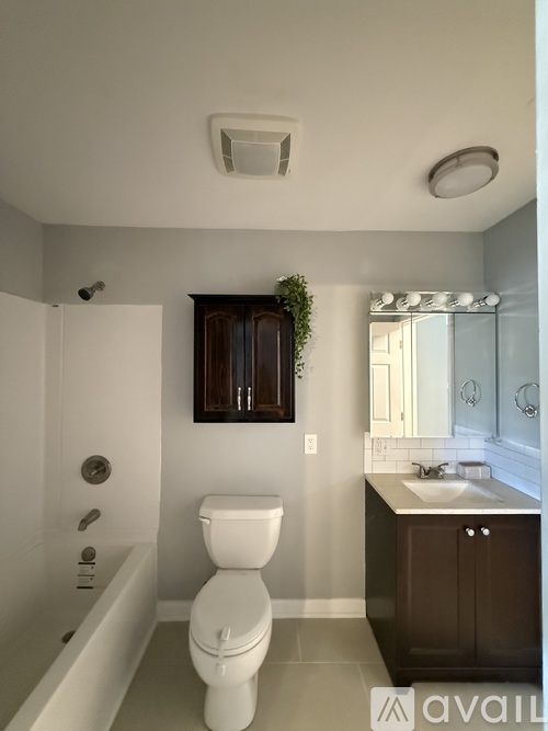 A white toilet in a bathroom with a white tub and a white sink.