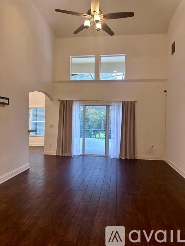 A spacious room with a ceiling fan and hardwood flooring.