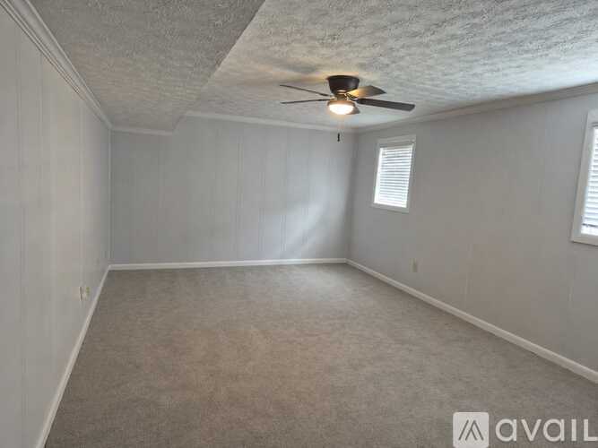 A room with a ceiling fan and carpeted floor.