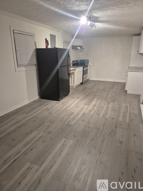 A kitchen with a black fridge and wooden flooring.