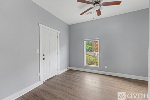 A room with a white door and a window showing a backyard.
