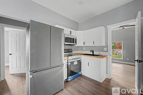 A kitchen with a refrigerator, microwave, oven, and sink.
