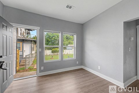 A room with a door and a window overlooking a backyard.
