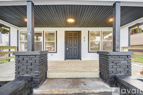 A house with a black front door and two stone pillars on either side.