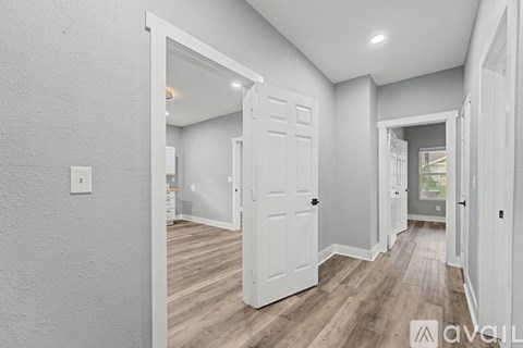 A hallway with white doors and wooden floors.