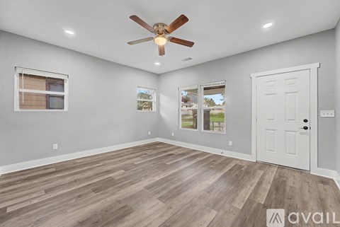A room with a ceiling fan and wooden flooring.