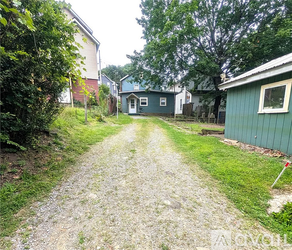 A gravel path leads to a small house in a residential area.