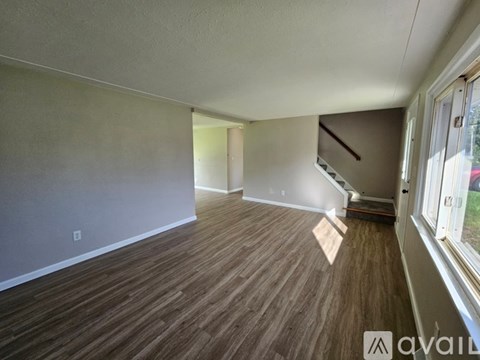 A room with wooden flooring and a window on the right side.