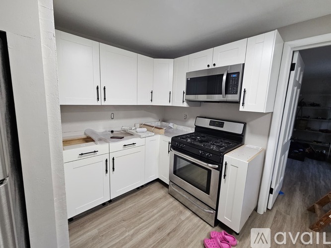 A kitchen with white cabinets and appliances is available for rent.