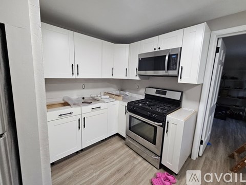A kitchen with white cabinets and appliances is available for rent.