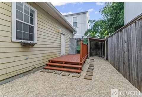 A backyard with a wooden deck and a gravel area.