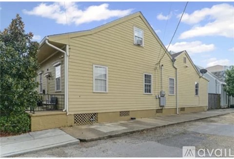 A yellow house with a porch and a small front yard.