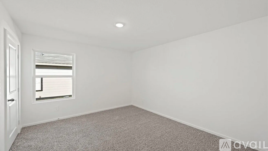 A room with a carpeted floor and a window with blinds.