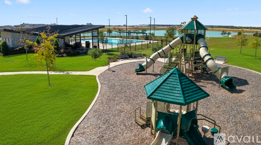 A playground with a green slide and a pool in the background.
