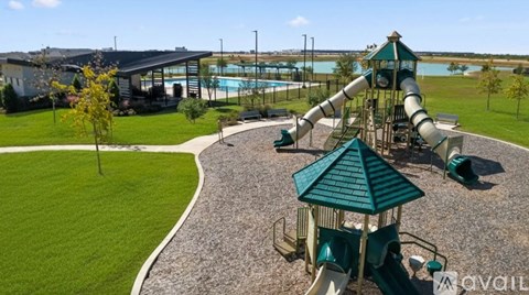 A playground with a green slide and a pool in the background.