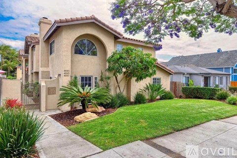 A beige house with a green lawn in front.
