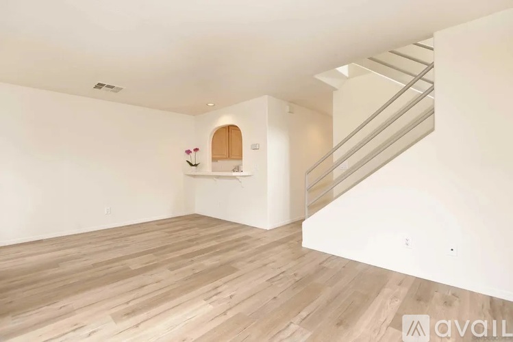 A spacious room with wooden flooring and a staircase.