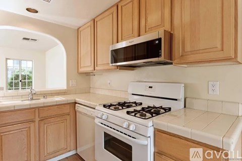 A kitchen with a white stove top oven and a microwave above it.