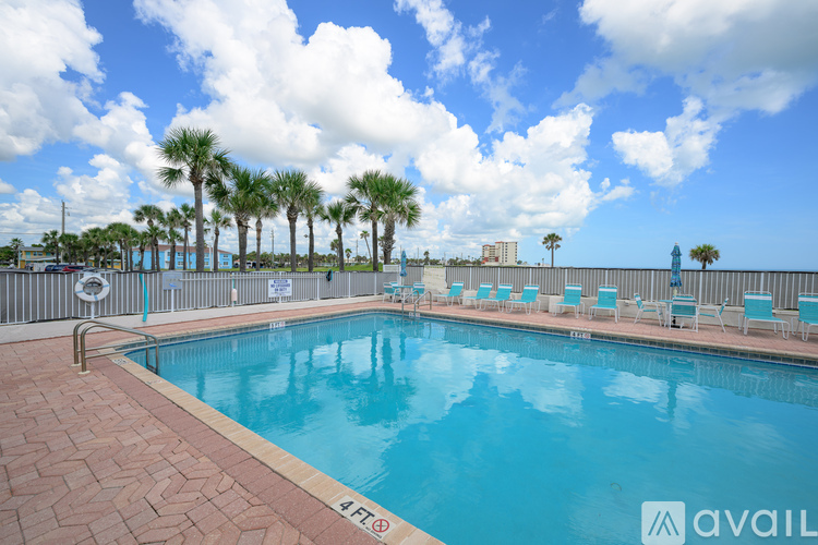 A pool surrounded by chairs and palm trees.