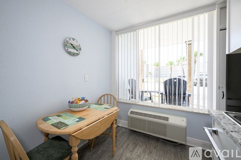 A kitchen with a table and chairs and a clock on the wall.