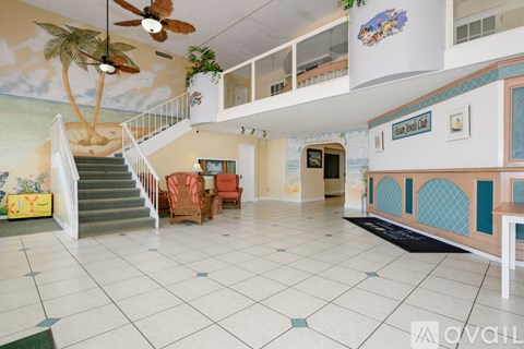 A living room with a staircase and a painting of a beach scene on the wall.