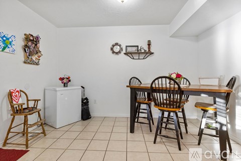 A dining room with a white wall and a wooden table.