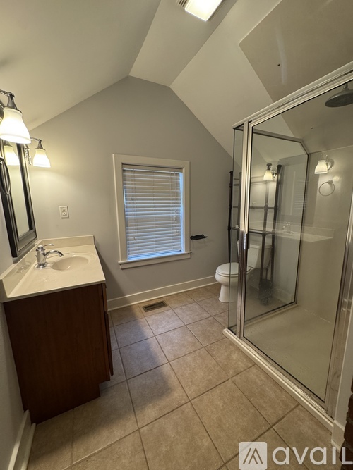 A bathroom with a sink, mirror, and shower.