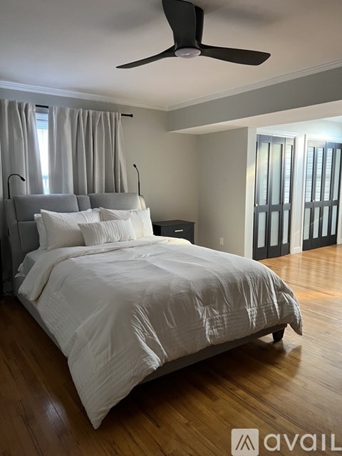 A bedroom with a large bed and a ceiling fan.