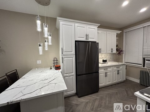 A kitchen with a marble countertop and a black refrigerator.
