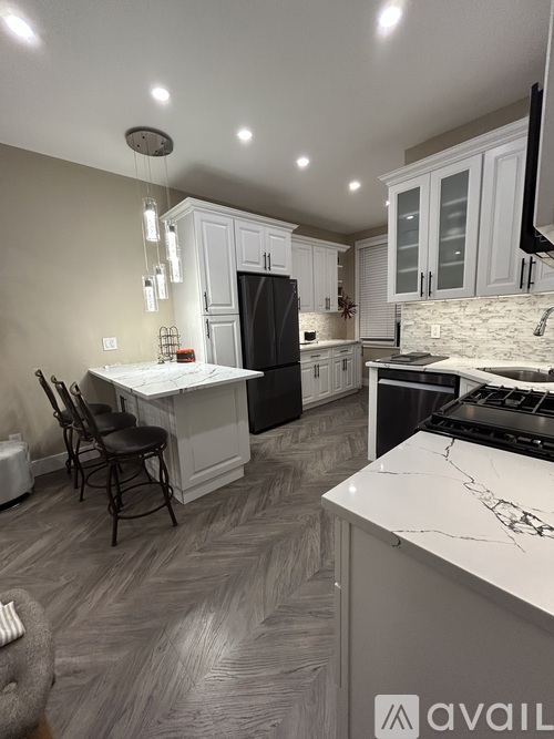 A kitchen with a marble countertop and a black refrigerator.