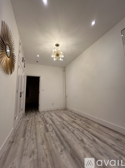 A hallway with a wooden floor and a wall-mounted mirror.