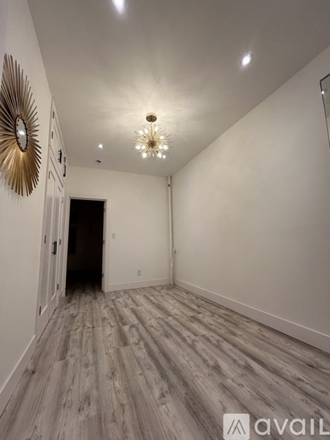 A hallway with a wooden floor and a wall-mounted mirror.