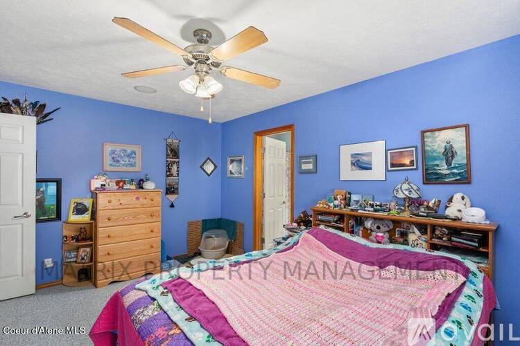 A bedroom with blue walls and a bed in the center.