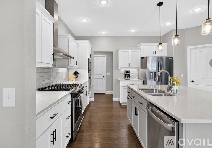 A modern kitchen with white cabinets and stainless steel appliances.