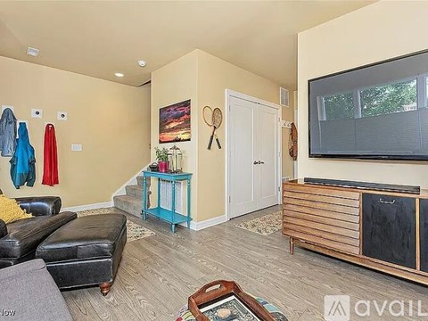 A living room with a black leather couch, a wooden cabinet, and a painting on the wall.