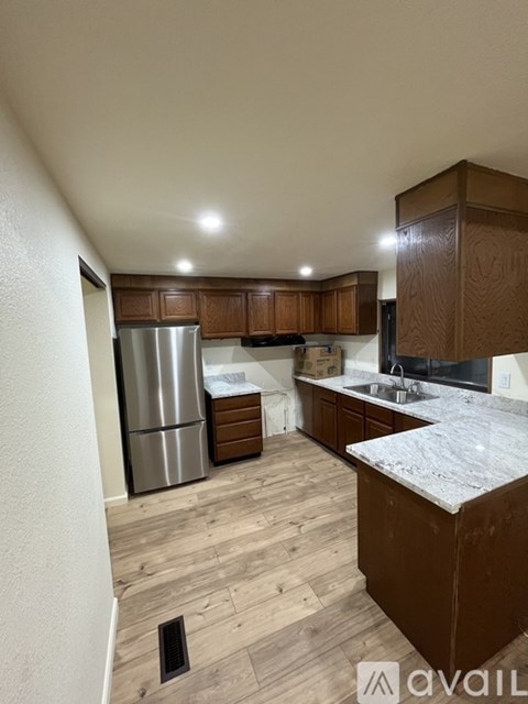 A kitchen with wooden cabinets and a marble countertop.