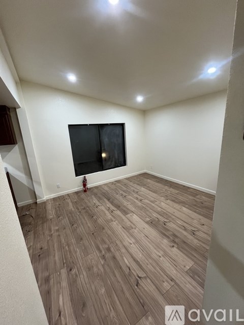 A room with wooden flooring and a flat screen TV mounted on the wall.