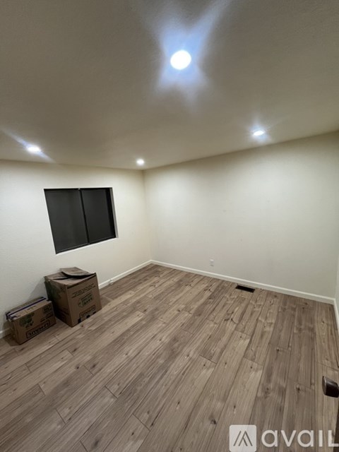 A room with wooden flooring and a flat screen TV mounted on the wall.