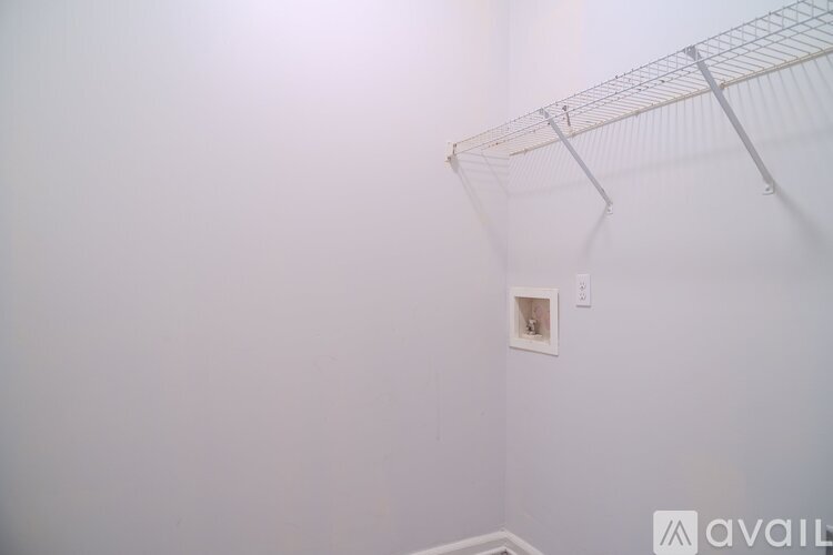 A white wall with a shelf and a light switch.