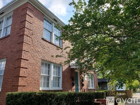 A red brick house with a green door and white windows.
