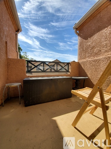 A wooden chair is in the foreground of a balcony with a hot tub and a wall with a logo on it.