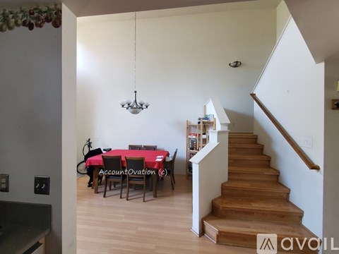 A dining room with a table set for six with a red tablecloth and chairs.