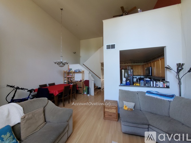 A living room with a grey couch and a dining table with chairs.
