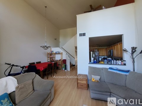 A living room with a grey couch and a dining table with chairs.