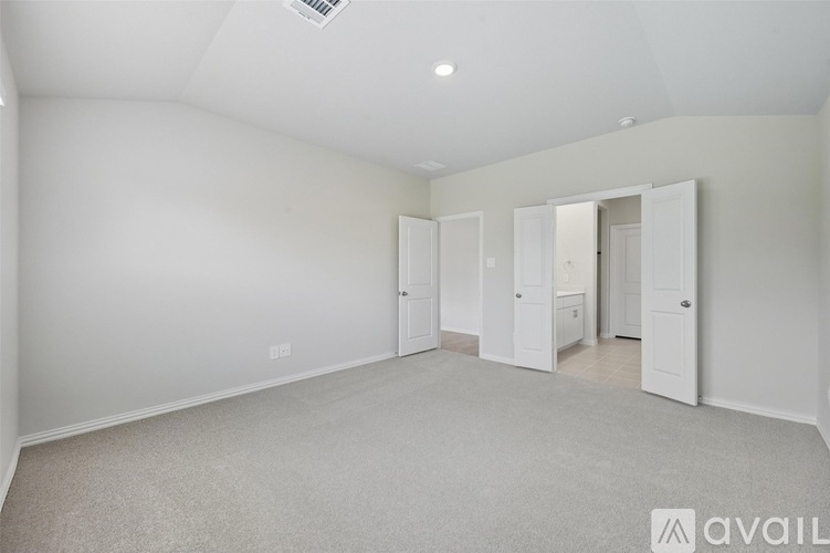 A spacious room with white walls and carpeted floor.