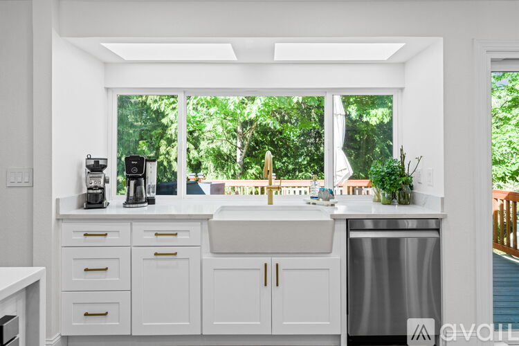 A kitchen with white cabinets and a window overlooking a green area.